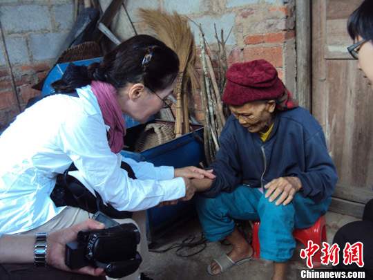 日本“海南島近代史研究會(huì)”創(chuàng)始人佐藤正人第22次到海南島調(diào)查日本侵瓊史。圖為在保亭黎族苗族自治縣南林鄉(xiāng)羅葵村，金靜美握著86歲老人林亞金的手。中新社發(fā) 張茜翼 攝